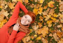 Devojka leži po opalom jesenjem lišću